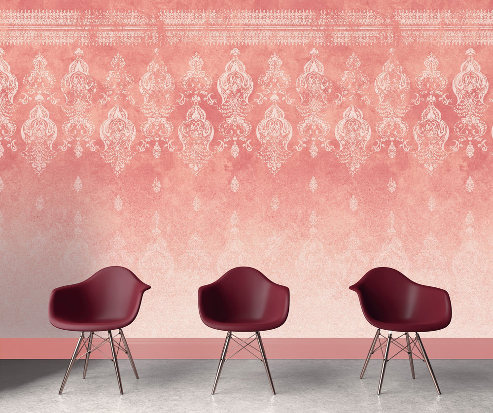 Pink distressed walls wallpaper with intricate vintage patterns behind three burgundy modern chairs