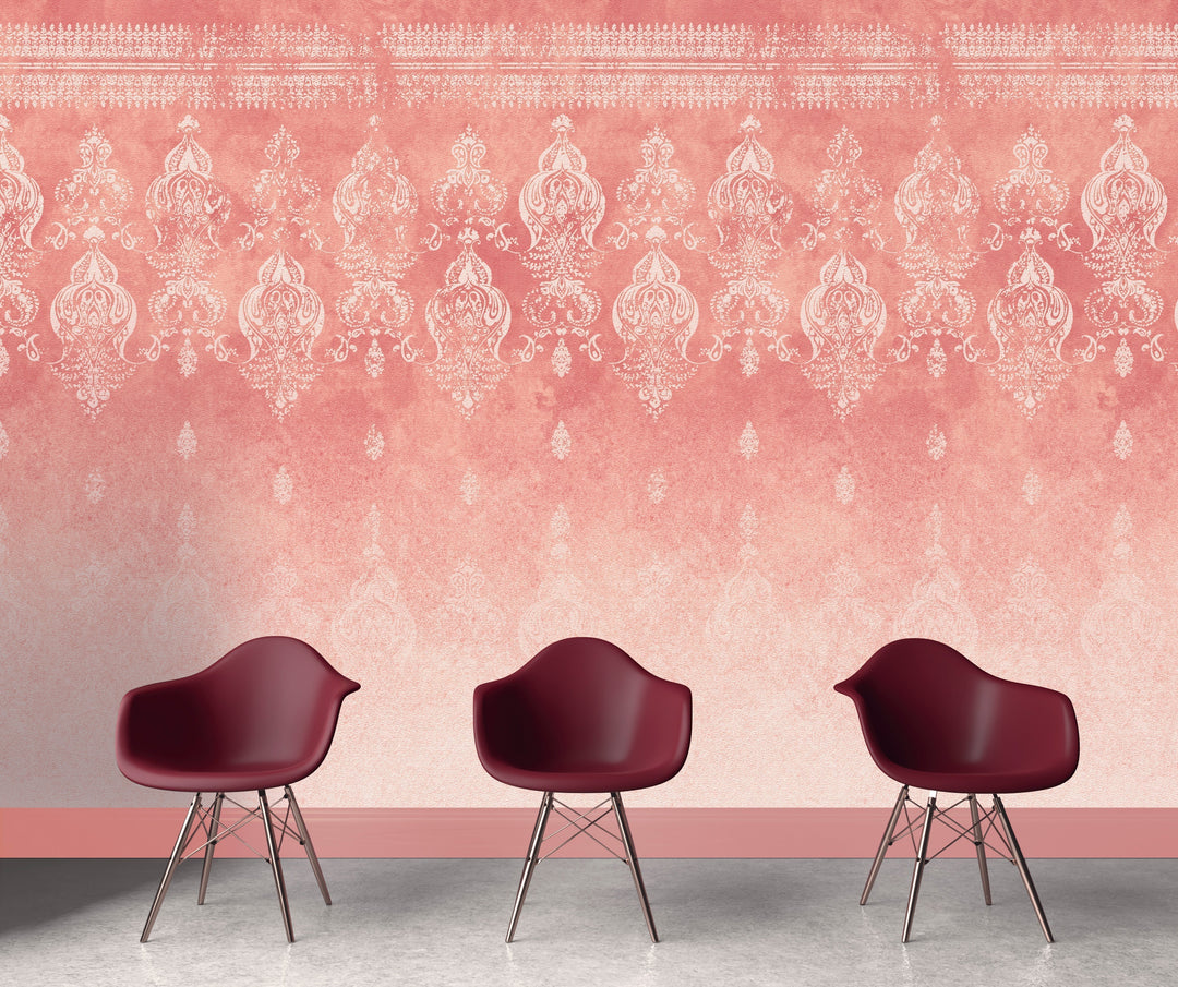 Pink distressed walls wallpaper with intricate vintage patterns behind three burgundy modern chairs