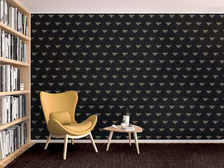 Modern interior with black bee wallpaper featuring elegant bee patterns, mustard yellow chair, wooden bookshelf, and small round table
