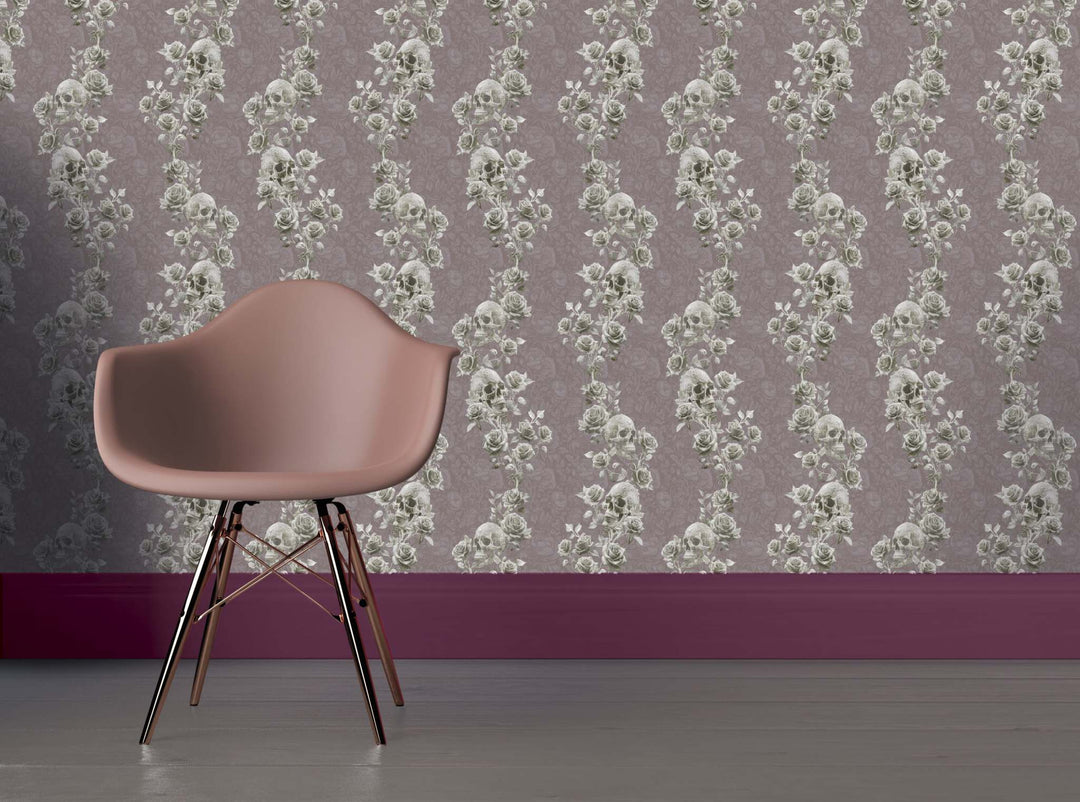 Blush pink chair against skulls and roses wallpaper with gothic floral pattern on mauve wall background